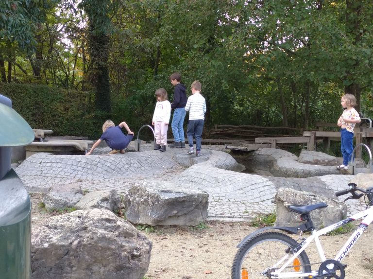 Kinderen van verschillende leeftijden spelen samen bij een waterspeelplaats in het park