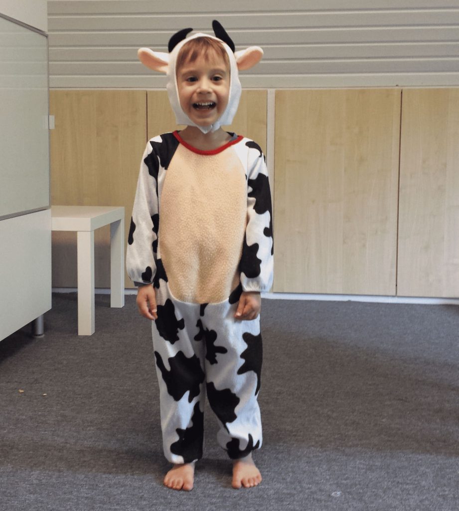 Kleuter verkleed als koe met carnaval, lachend op blote voeten